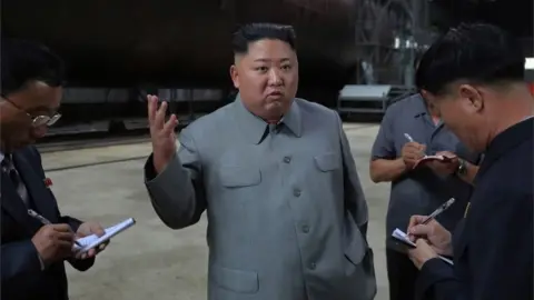 European Photopress Agency A photo released by the official North Korean Central News Agency (KCNA) on 23 July 2019 shows Kim Jong-Un (C), speaking to officials after making a round of the newly-laid down submarine at an undisclosed location in North Korea.