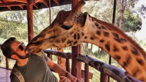 Triphackr A giraffe licks Triphackr founder Clint Johnston