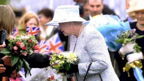 Getty Images Queen Elizabeth II greets the crowd in Ballinamallard, County Fermanagh, during the first full day of her Golden Jubilee tour of Northern Ireland in 2002