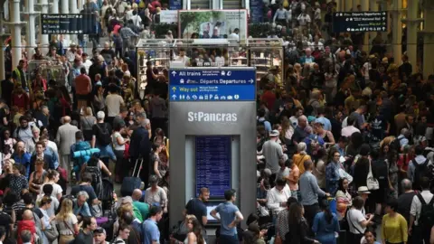 EPA/ANDY RAIN Passengers wait for trains at St Pancras International station in London