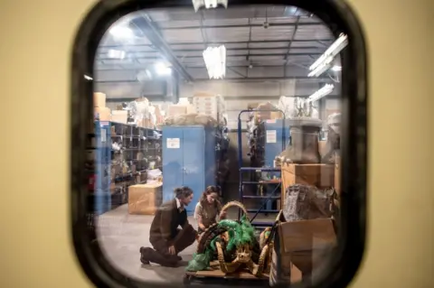 BBC The two investigators spotted through a window examining ibex parts