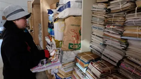 Getty Images A worker sorts newspapers and magazines for recycling in the "eco-town" of Kamikatsu