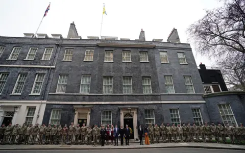 Jordan Pettitt/PA Prime Minister Rishi Sunak is joined by the Ukrainian Ambassador to the UK, Vadym Prystaiko, his wife Inna Prustaiko, members of the Ukrainian Armed Forces, and representatives from each Interflex nation, outside 10 Downing Street, London, 24 February 2023.