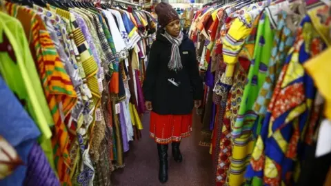 EPA Woman looks at rails of African clothing