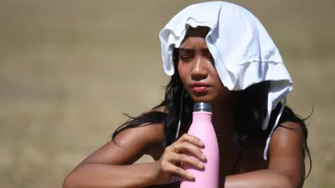EPA A woman cools herself as she sunbathes in St James' Park in London, Britain, 07 August 2020.