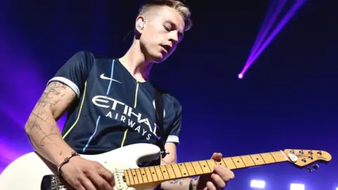 A close-up photo of James Brittain-McVey playing guitar