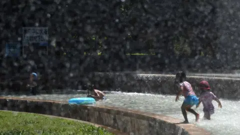 Getty Images Children play in a water fountain in a Tokyo park, as a heatwave grips Japan, 10 July 2018