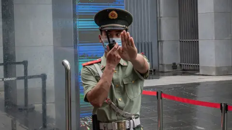 Getty Images A Chinese police officer gestures "stop" outside the Australian embassy in Beijing in July 2020