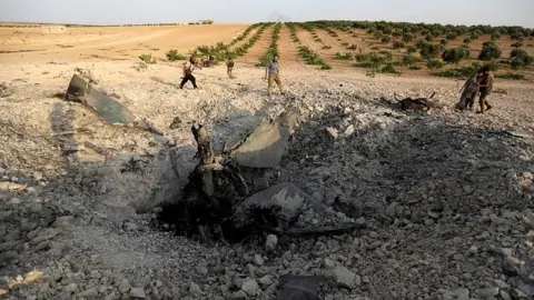 AFP Large crater where the plane hit the ground in Idlib