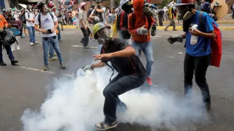 Ronald Grant A demonstrator prepares to throw a tear gas canister during riots at a rally against Venezuelan President Mauro's government in Caracas, Venezuela, June 7, 2017.