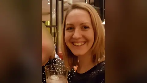 Unknown Social media image of Lucy Letby smiling at the camera and holding a drink