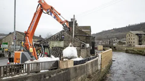 PA Media Workers construct flood defences in Mytholmroyd ahead of Storm Dennis