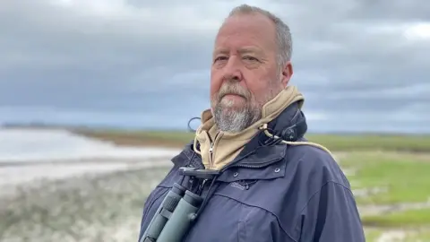 Pete Simson/BBC Birdwatcher Paul Bowerman standing on the banks of the River Severn near Bristol