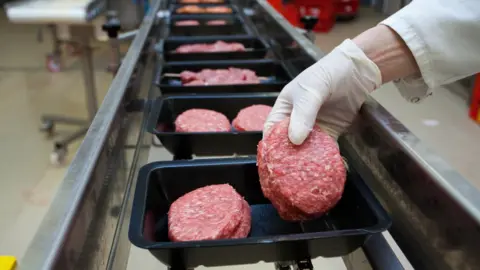 Getty Images Man placing meat on factory line