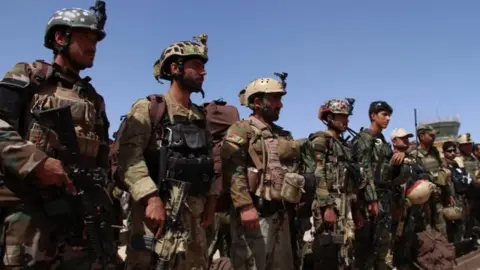 EPA Afghan soldiers stand guard as people who were freed by Afghan security forces from a prison run by Taliban militants, are brought to a military base in Helmand, Afghanistan, 31 May 2018.