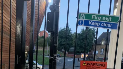 Ryan Gleeson A fire exit with wire wrapped around the gate