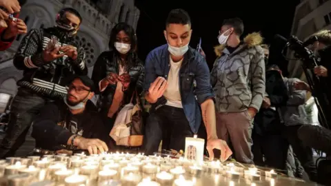 Getty Images People lights candle outside the Notre-Dame de l'Assomption Basilica in Nice on October 29, 2020