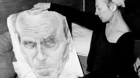 Getty Images Lucette Destouches holds up a portrait of her husband Louis-Ferdinand Céline in 1969