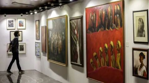 EPA A viewer inspecting the paintings at the auction