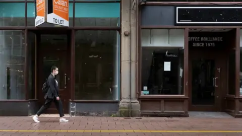 Getty Images A woman walking along Cardiff street with empty shops behind