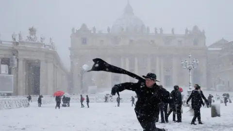 Reuters A young priest throws a snowball in St Peter's Square, Vatican