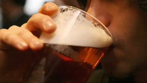 PA Media Man drinking a pint of beer