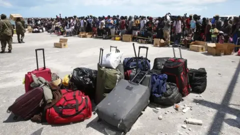 Getty Images Hurricane Dorian survivors wait to evacuated in private boats at the Marsh Harbour port on Grand Abaco Island