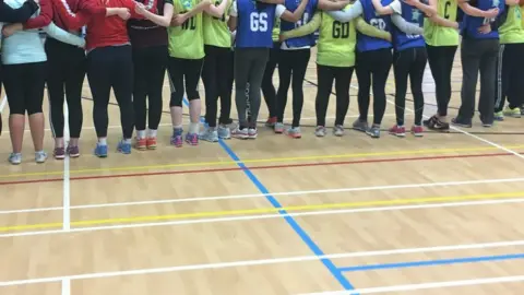 Heather Lewis The team in a line from behind wearing netball bibs