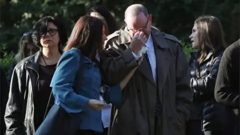 Reuters Mourners tear up and hold each other while waiting to pay respects