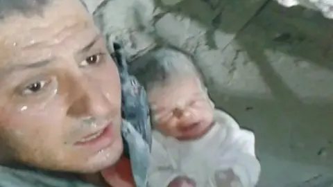 Khaled Omar Harrah with a baby rescued from rubble