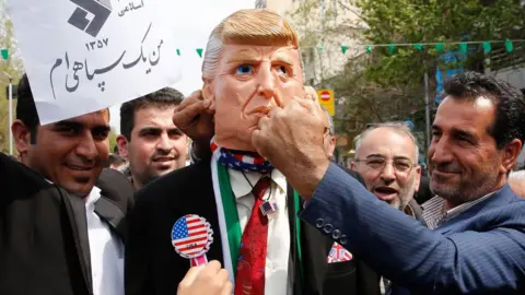 AFP Iranians pretend to hit a man wearing a mask of US President Donald Trump, at a rally in Tehran on 12 April 2019