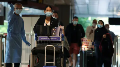 Reuters Travellers wearing masks arrive at Singapore Airport