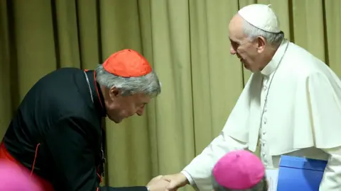 Getty Images Cardinal Pell, left, bows his head as he sakes the and of Pope Francis in this 2015 photo