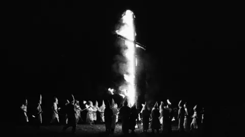 Laura Camden via Getty Images KKK members gather for a cross burning in 1994