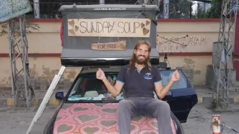 Dominika Maria Uwe on the bonnet of the touring car in Lahore
