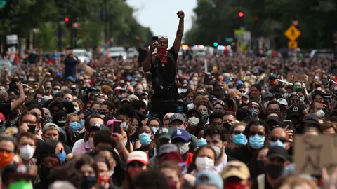 Getty Images A man holds up his fist while hundreds of demonstrators march to protest against police brutality and the death of George Floyd, on June 2, 2020 in Washington, DC.