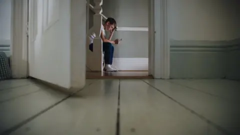 Getty Images A boy sat on the stairs using his phone