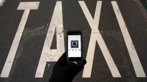 Reuters Uber app and a taxi sign on the ground