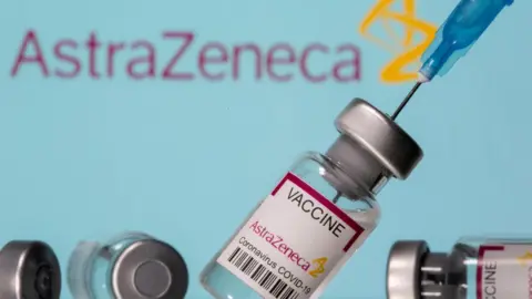 Reuters Vials labelled "Astra Zeneca COVID-19 Coronavirus Vaccine" and a syringe are seen in front of a displayed AstraZeneca logo, in this illustration photo taken March 14, 2021.