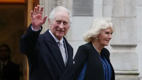 EPA King Charles smiles and waves as he leaves hospital accompanied by a smiling Camilla