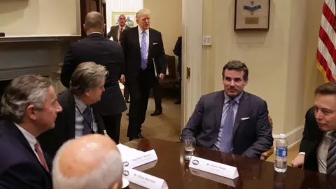 Getty Images President Donald Trump walks into the Roosevelt Room for a meeting with Mark Sutton of International Paper, Jeff Fettig of Whirlpool, White House Senior Counselor Steve Bannon, Kevin Plank of Under Armour, Elon Musk of SpaceX (L) and other other business leaders at the White House on 23 January 2017 in Washington, DC.