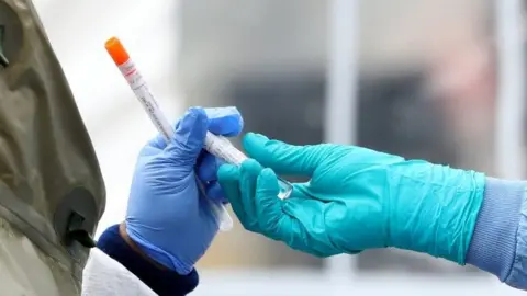 Getty Images Medical professionals pass each other a coronavirus test at a drive-thru testing site at Cambridge Health Alliance Somerville Hospital on April 28, 2020 in Somerville, Massachusetts.