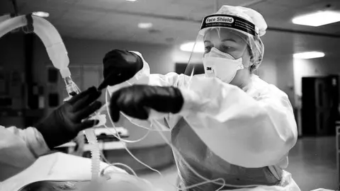 BBC ICU Charge Nurse Morag Malcolm helps arrange the delicate web of monitor wires and the ventilation tubing that keeps a Covid patient alive.