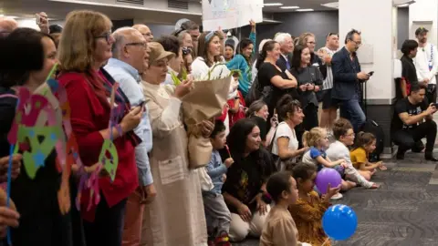 Getty Images Families wait to be reunited as travellers arrive on the first flight from Sydney,