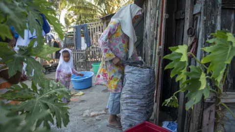 BBC/Shiraaz Mohamed A young girl prepares a bag of coal to be used for cooking in preparation for Eid food in Fort Dauphin, Madagascar