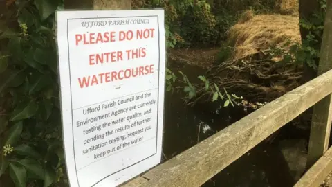 A warning sign that has been put up by Ufford Parish Council warning people not to enter the water due to water quality tests taking place