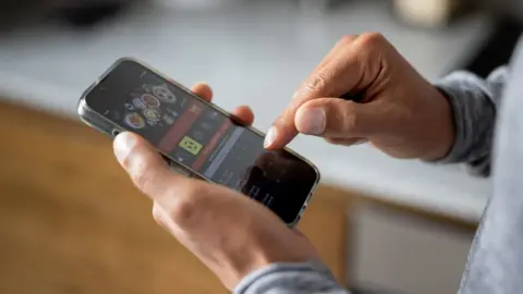 Getty Images Close-up on a man betting online on a sports app on his mobile phone