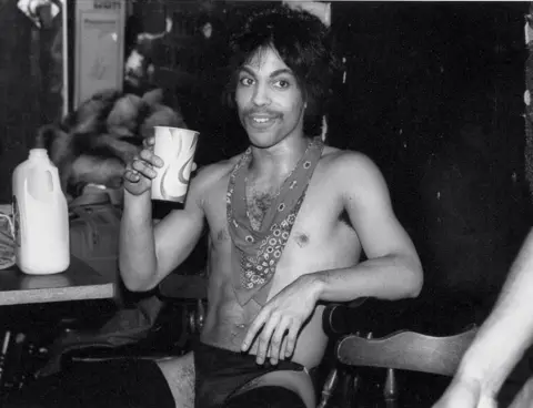 1985 Allen Beaulieu Prince sips some orange juice backstage during the Dirty Mind tour, 1981