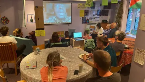 SISTER People at the community centre watching a film on a projector