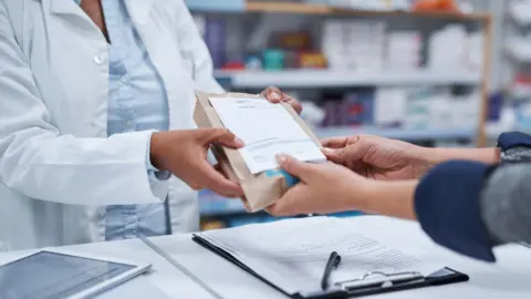 Getty Images Pharmacist handing over a prescription